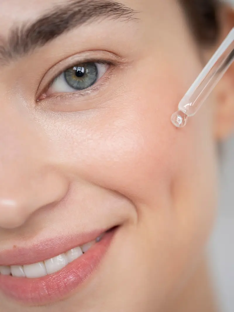 Portrait of beautiful woman with clear skin using face serum