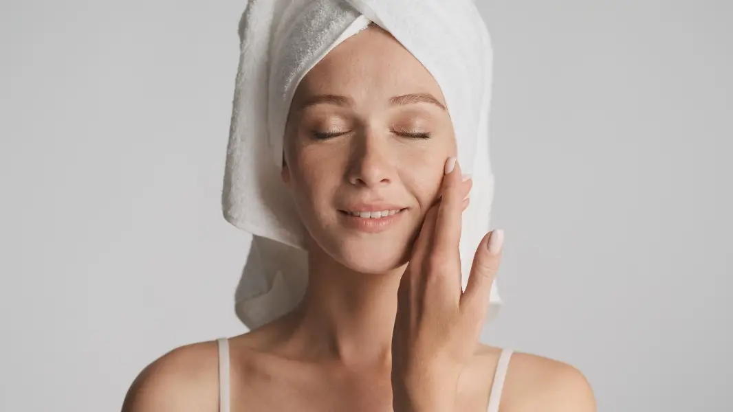 Beautiful girl with smooth healthy skin and towel on head sensually posing on camera isolated. Beauty concept